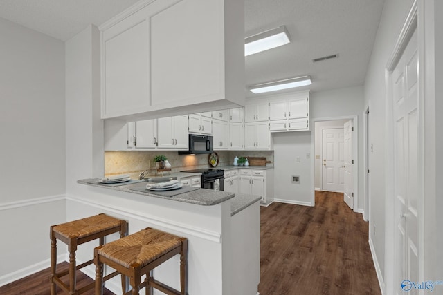 kitchen with kitchen peninsula, white cabinets, and black appliances