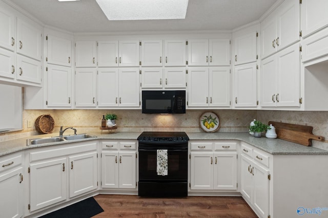 kitchen with a skylight, white cabinetry, sink, and black appliances