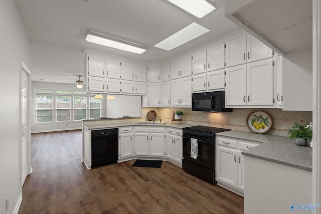 kitchen featuring black appliances, white cabinets, a skylight, dark hardwood / wood-style floors, and tasteful backsplash