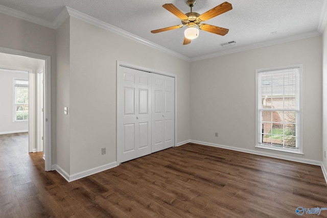 unfurnished bedroom with dark wood-type flooring, ceiling fan, ornamental molding, a textured ceiling, and a closet