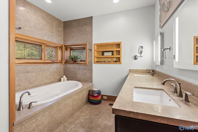 bathroom with tile patterned flooring, vanity, and tiled bath