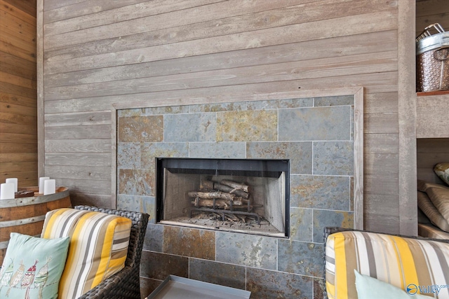 interior details featuring a tile fireplace and wood walls