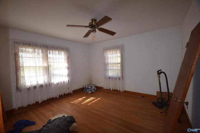 unfurnished room featuring a ceiling fan, wood finished floors, and baseboards
