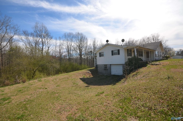 view of side of home with a yard, driveway, and an attached garage