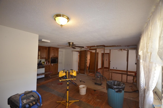 below grade area with a textured ceiling, wood finished floors, and a ceiling fan
