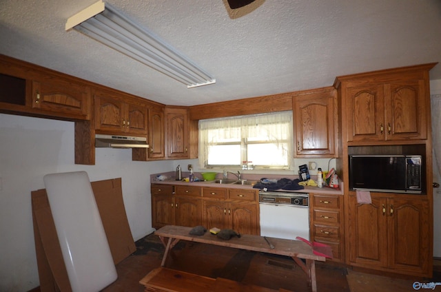 kitchen with a sink, under cabinet range hood, black microwave, dishwasher, and brown cabinets