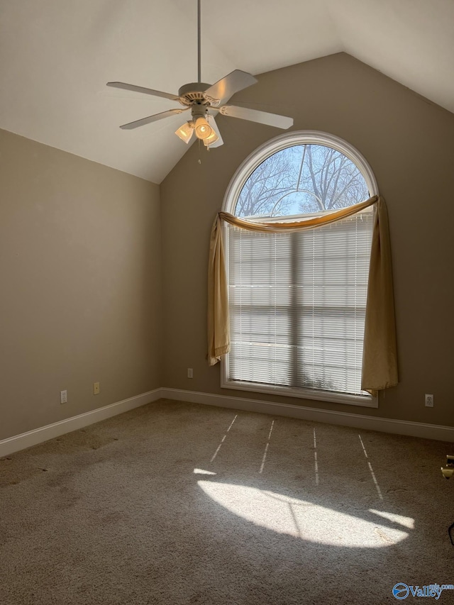 empty room featuring vaulted ceiling, carpet flooring, a ceiling fan, and baseboards