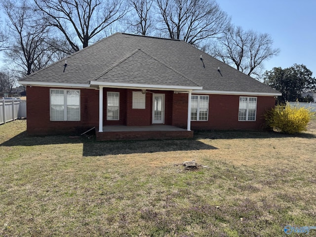 back of house featuring a patio area, a lawn, brick siding, and fence