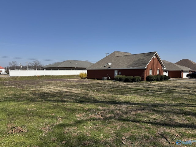 view of home's exterior featuring fence, a lawn, and central AC