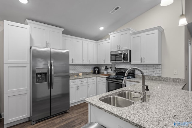 kitchen featuring vaulted ceiling, white cabinetry, sink, hanging light fixtures, and stainless steel appliances