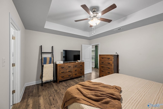 bedroom featuring dark wood-type flooring, a raised ceiling, and ceiling fan