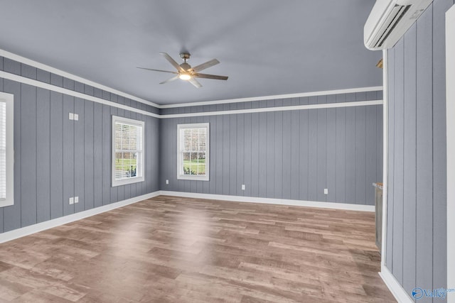 spare room featuring a ceiling fan, baseboards, light wood finished floors, and a wall mounted AC