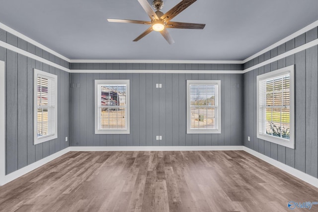 empty room featuring a healthy amount of sunlight, wood finished floors, and baseboards