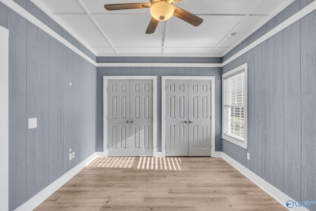 unfurnished bedroom with baseboards, a ceiling fan, light wood-style flooring, and multiple closets