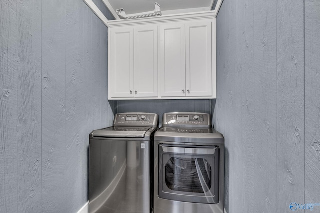 washroom featuring a textured wall, washing machine and dryer, and cabinet space