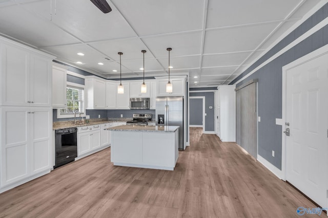 kitchen featuring a center island, pendant lighting, stainless steel appliances, white cabinetry, and light stone countertops