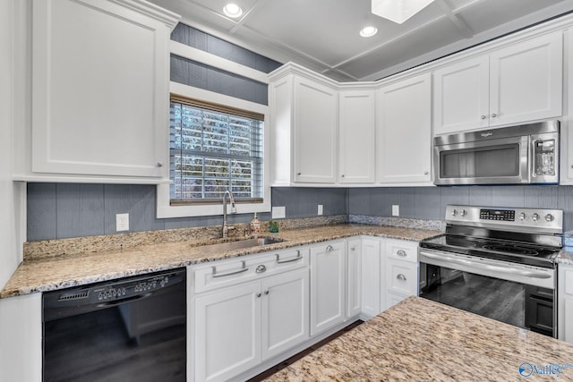 kitchen with white cabinetry, appliances with stainless steel finishes, light stone counters, and a sink