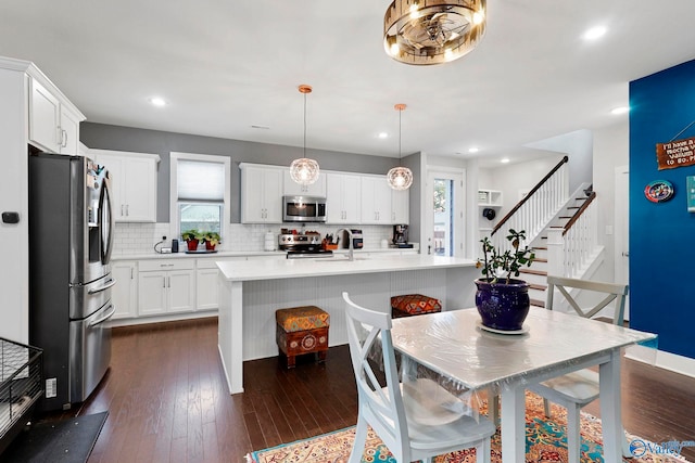 kitchen with dark wood-type flooring, white cabinets, light countertops, appliances with stainless steel finishes, and decorative backsplash