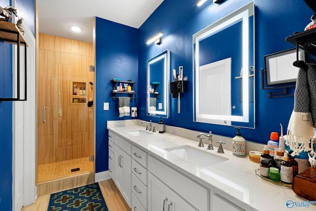 bathroom with double vanity, a stall shower, and a sink