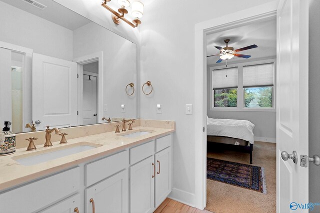 ensuite bathroom featuring double vanity, baseboards, visible vents, and a sink