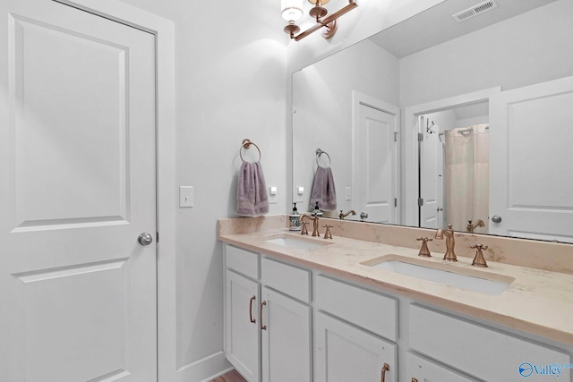 bathroom with visible vents, a sink, and double vanity