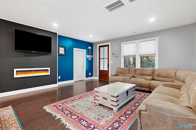 living room featuring baseboards, visible vents, wood finished floors, a fireplace, and recessed lighting