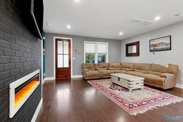 living room featuring recessed lighting, dark wood-type flooring, visible vents, baseboards, and heating unit