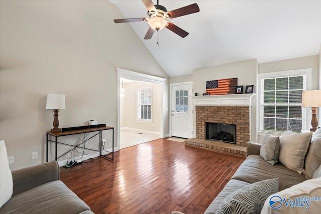 living room featuring wood-type flooring, high vaulted ceiling, a brick fireplace, and ceiling fan