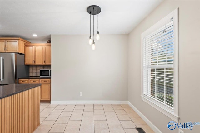 kitchen featuring backsplash, hanging light fixtures, light tile patterned floors, and stainless steel appliances