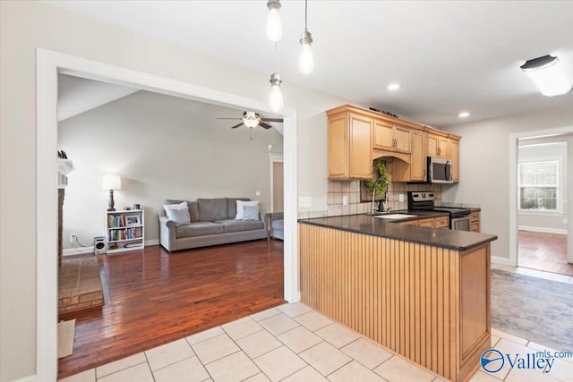 kitchen featuring pendant lighting, decorative backsplash, light hardwood / wood-style floors, kitchen peninsula, and stainless steel appliances