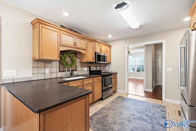 kitchen featuring kitchen peninsula, appliances with stainless steel finishes, backsplash, a textured ceiling, and sink