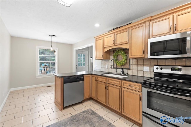 kitchen with pendant lighting, sink, decorative backsplash, kitchen peninsula, and stainless steel appliances