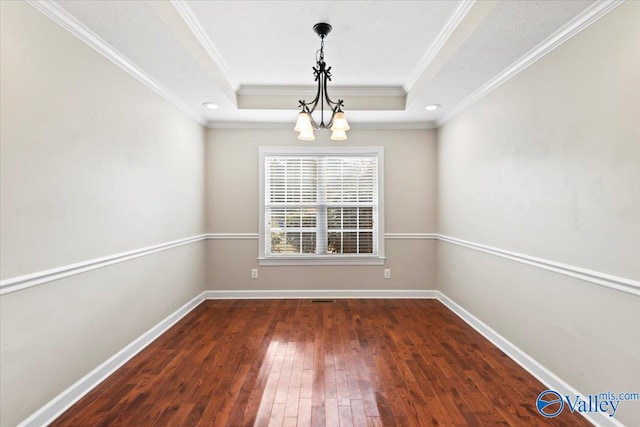 spare room featuring a chandelier, dark hardwood / wood-style floors, a tray ceiling, and crown molding