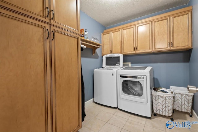 laundry room featuring washer and clothes dryer, cabinets, light tile patterned floors, and a textured ceiling