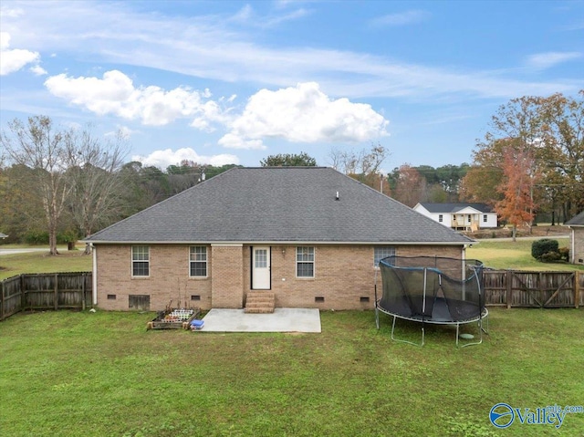 rear view of house with a yard, a patio, and a trampoline