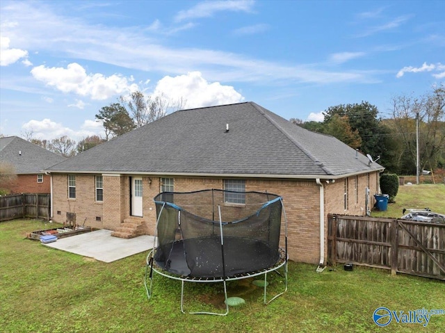 rear view of house with a lawn, a patio area, and a trampoline