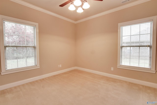 carpeted spare room with baseboards, ceiling fan, ornamental molding, and plenty of natural light