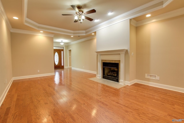 unfurnished living room with a tray ceiling, a fireplace with flush hearth, baseboards, light wood finished floors, and ceiling fan