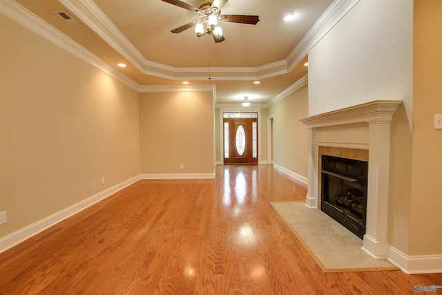 unfurnished living room with baseboards, a raised ceiling, light wood finished floors, a ceiling fan, and a fireplace
