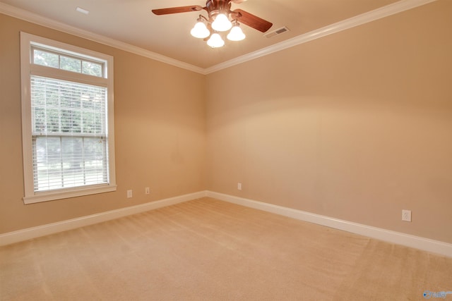 spare room featuring crown molding, light colored carpet, baseboards, ceiling fan, and visible vents