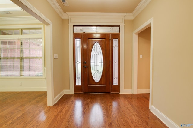 entrance foyer with baseboards, visible vents, wood finished floors, and crown molding
