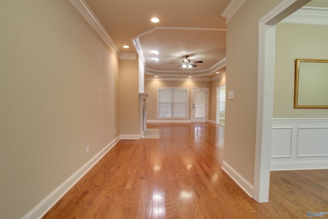 corridor with crown molding, light wood finished floors, a decorative wall, baseboards, and recessed lighting