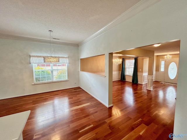 interior space featuring plenty of natural light, dark hardwood / wood-style floors, ornamental molding, and a chandelier