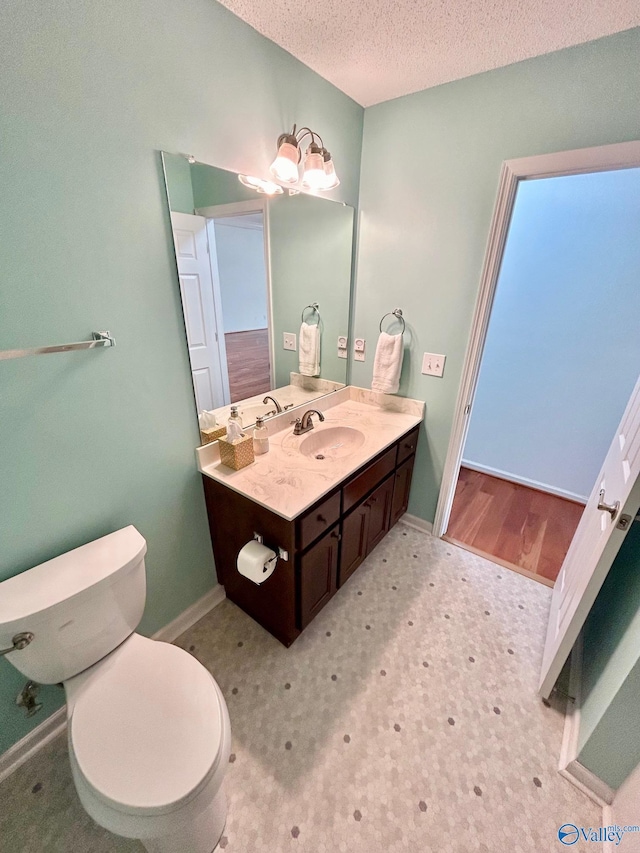 bathroom with a notable chandelier, vanity, a textured ceiling, and toilet