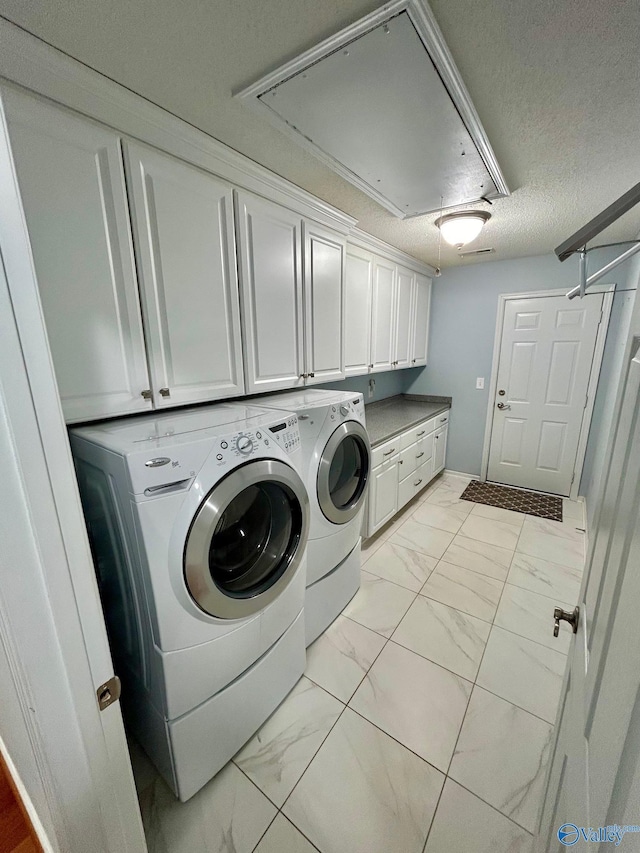 clothes washing area featuring cabinets, independent washer and dryer, and a textured ceiling