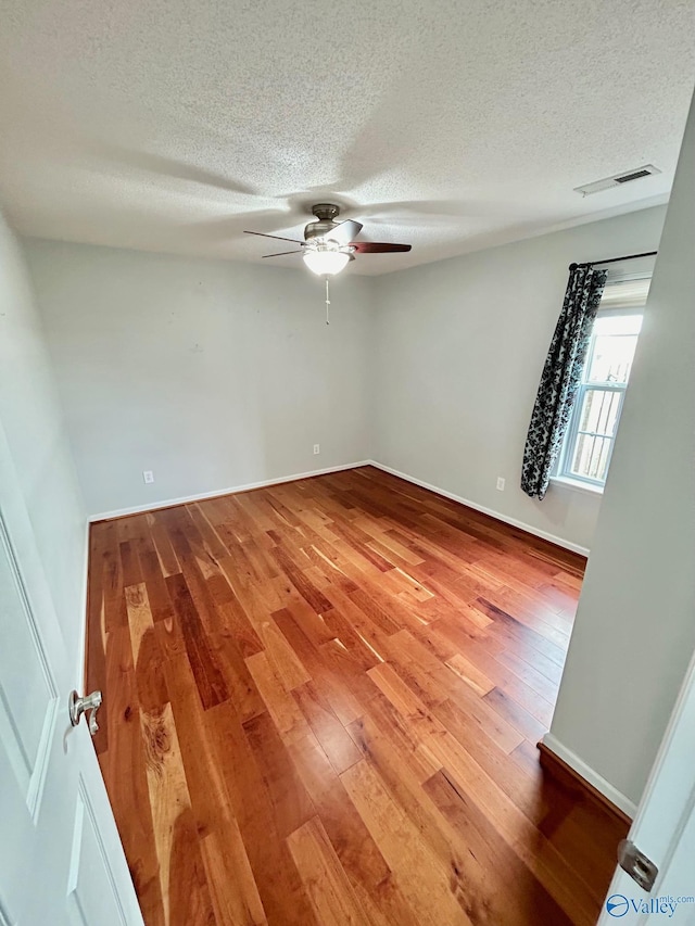 unfurnished room with ceiling fan, hardwood / wood-style floors, and a textured ceiling