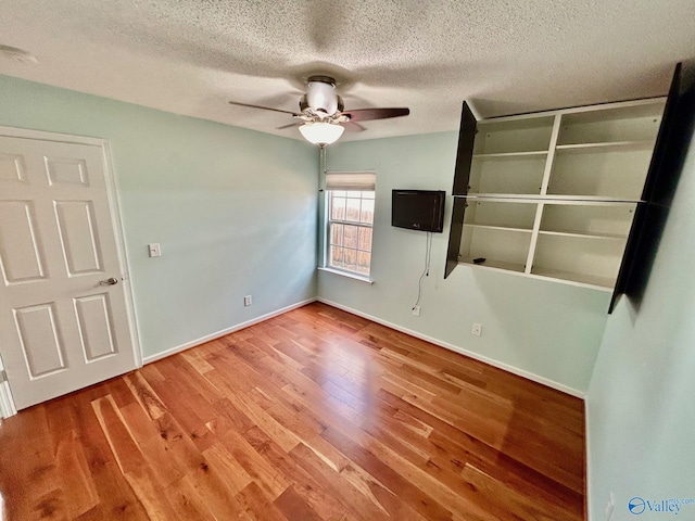 unfurnished bedroom with wood-type flooring, a textured ceiling, and ceiling fan