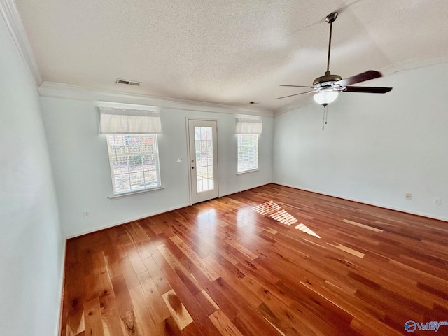 spare room with a textured ceiling, ceiling fan, wood-type flooring, and crown molding