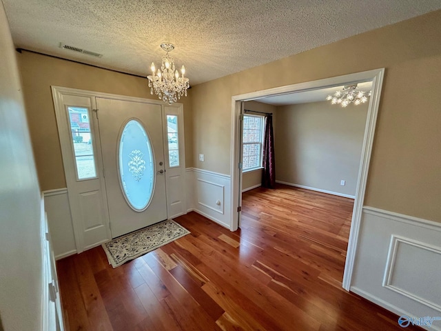 entryway with wood-type flooring, a textured ceiling, and an inviting chandelier