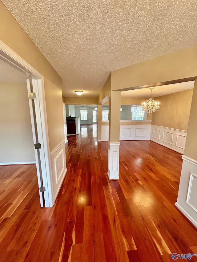 interior space with decorative columns, hardwood / wood-style flooring, a textured ceiling, and a notable chandelier